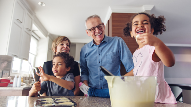 Two older grandparents making cupcakes with their grandchildren