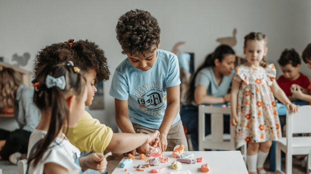 Children playing with model clay in a classroom.